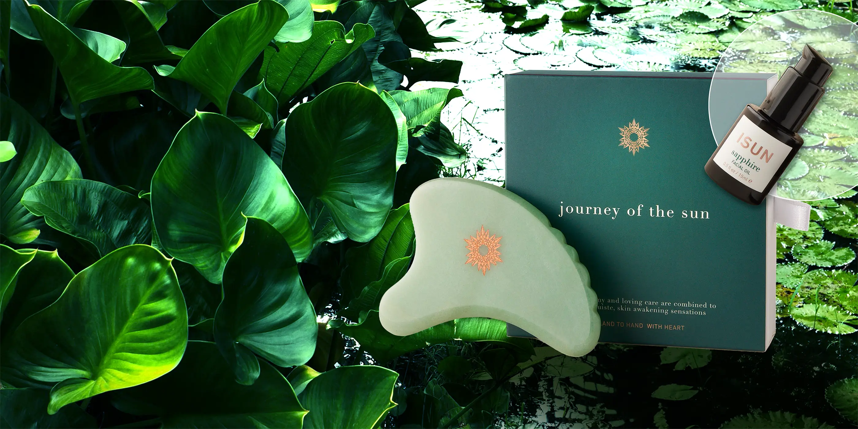 Aventurine gua sha tool with a box labeled 'journey of the sun' against a natural leafy background