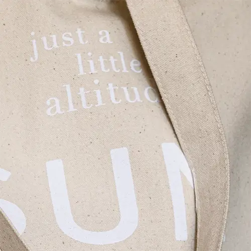 Beige tote bag with white text 'just a little altitude sun'