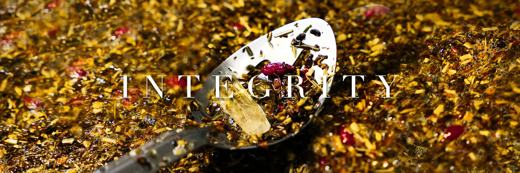 A spoon with a quartz crystal laying amongst a herb oil infusion