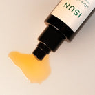 ISUN after shave balm with a droplet of yellow liquid on a beige background