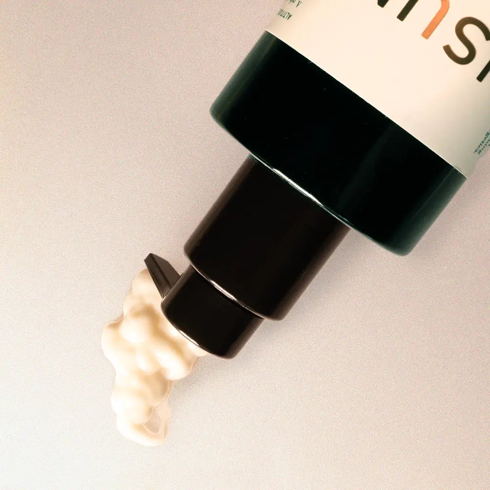 Cosmetic bottle with black cap and visible brand name on a light background