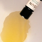 Bottle of ISUN essential oil with a yellow droplet on a light background