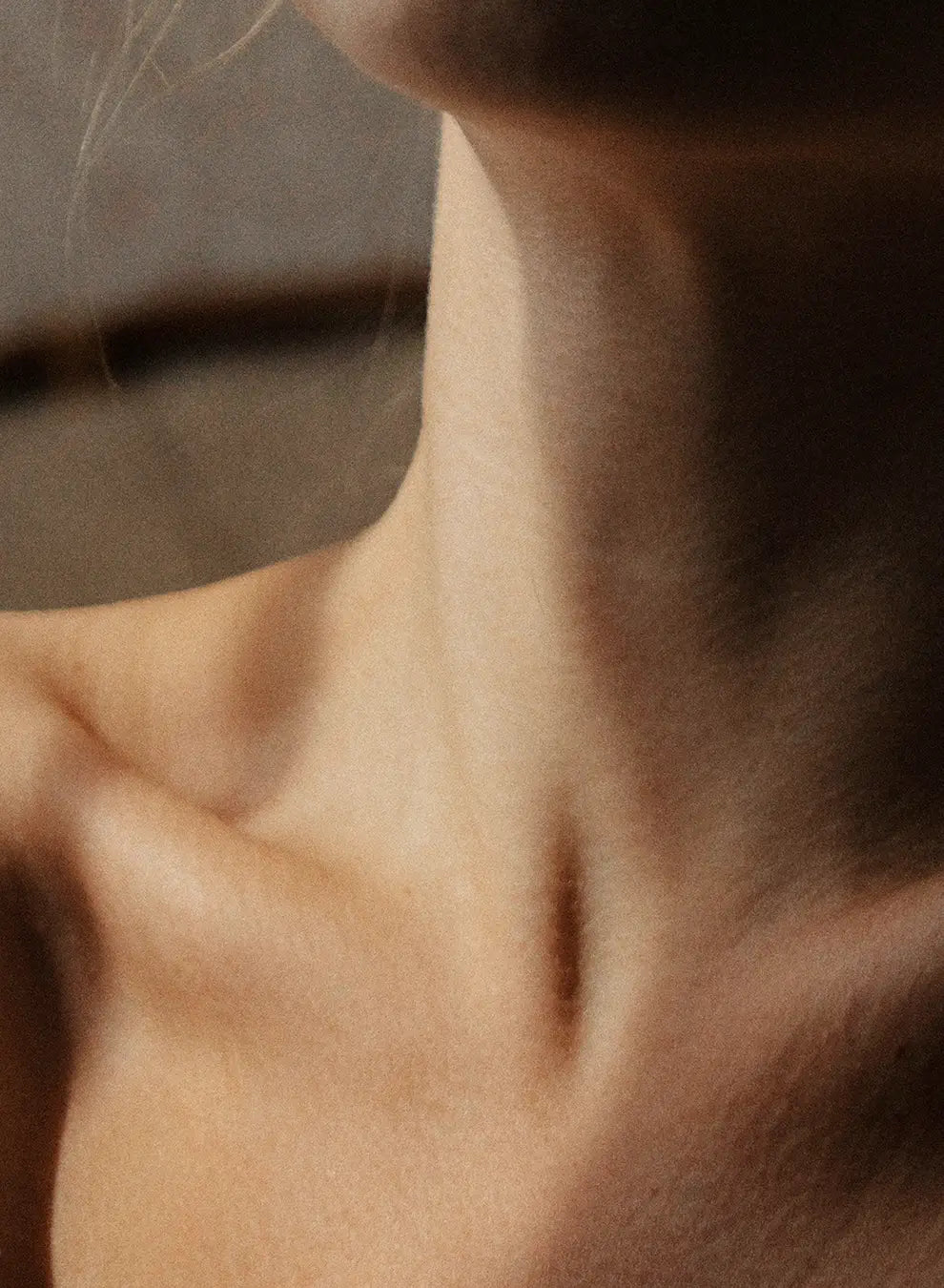 Close-up of a person's neck and shoulder with a blurred background
