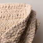 Close-up of a beige woven face cloth with a neutral background