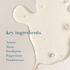 White liquid with text listing key ingredients on a light background
