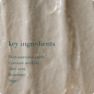 Close-up of a beige cosmetic product with text listing key ingredients on a beige background