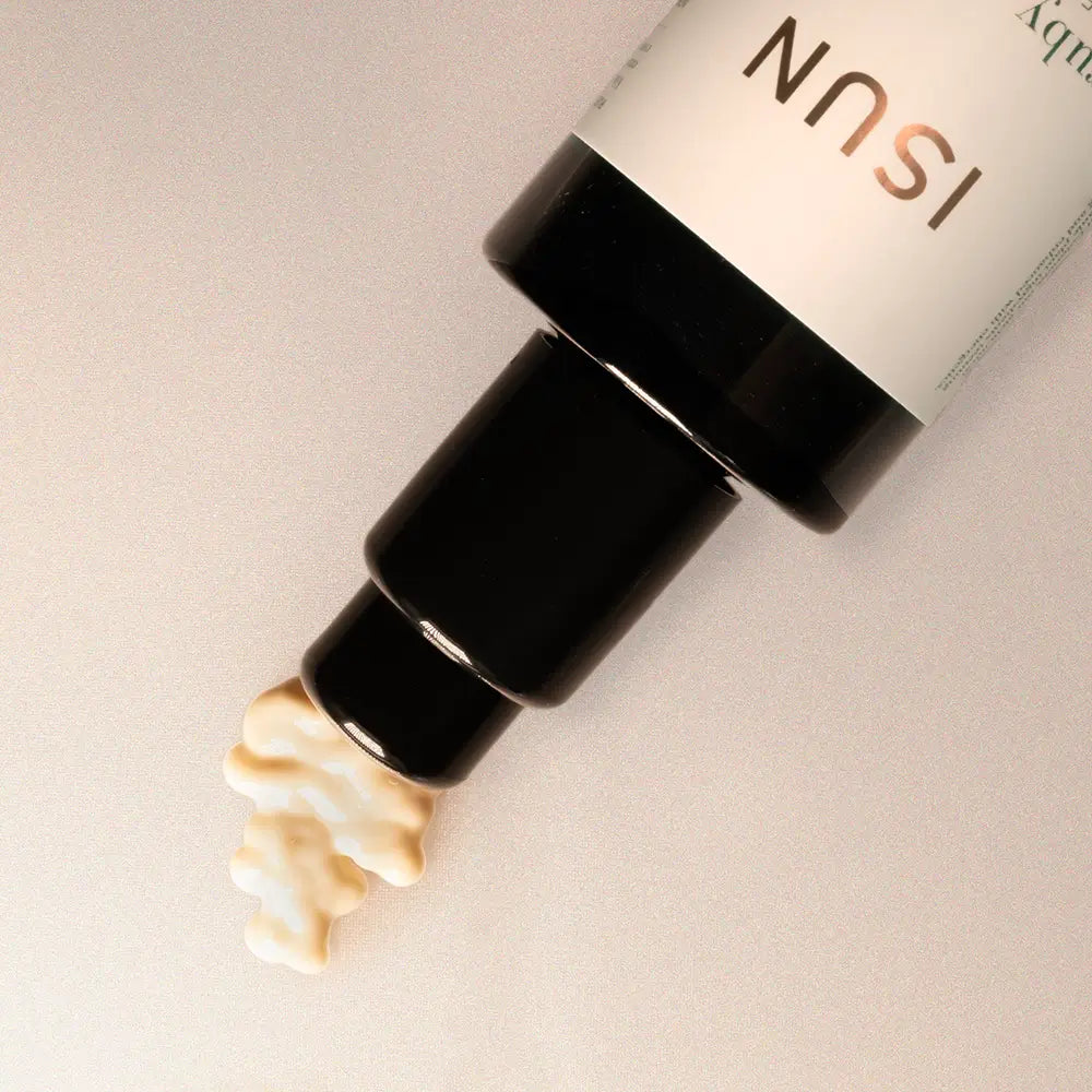 Cosmetic bottle with cream being pumped out on a neutral background