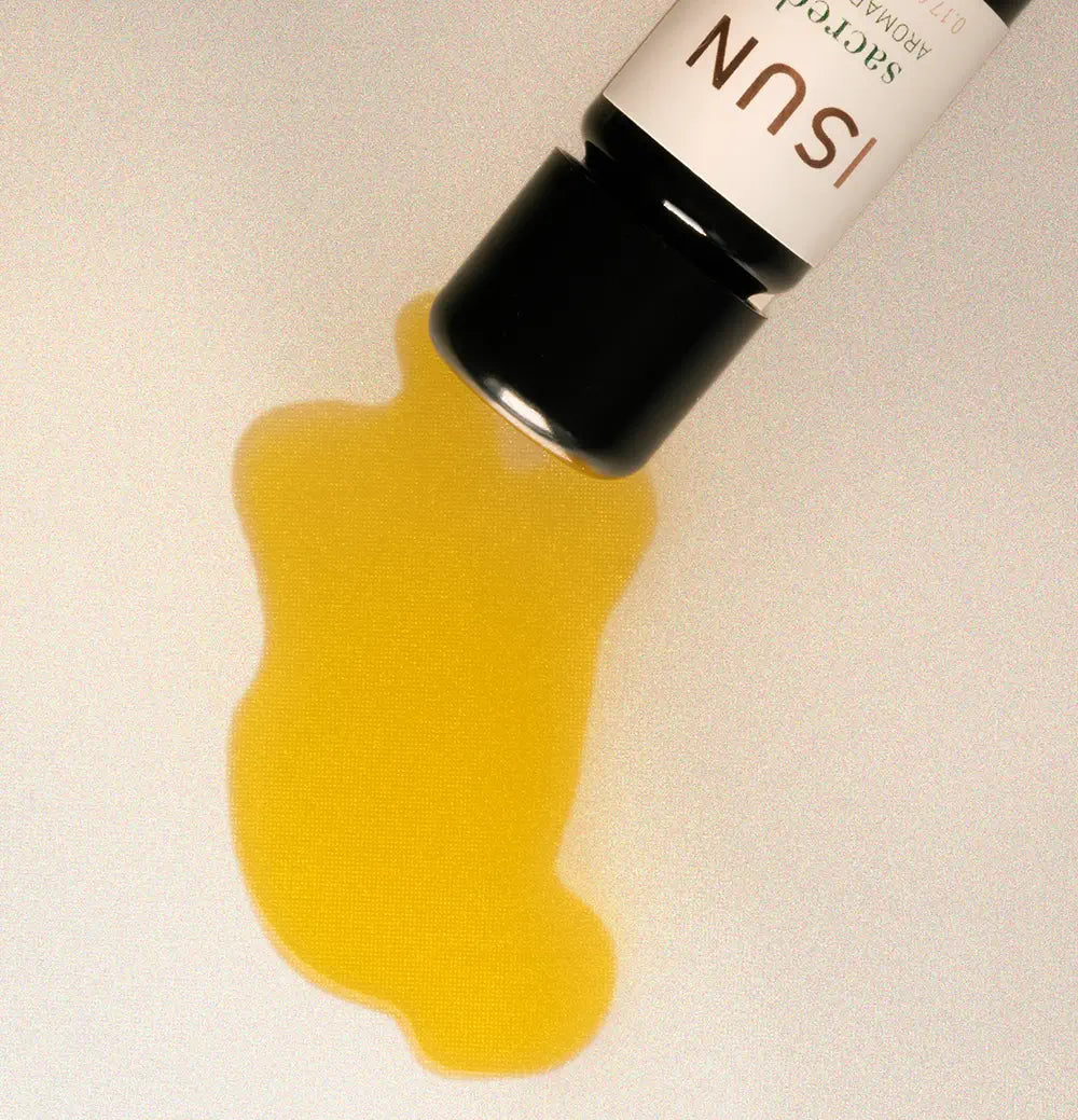 Yellow liquid spilling from a bottle labeled 'Sacred' on a white background