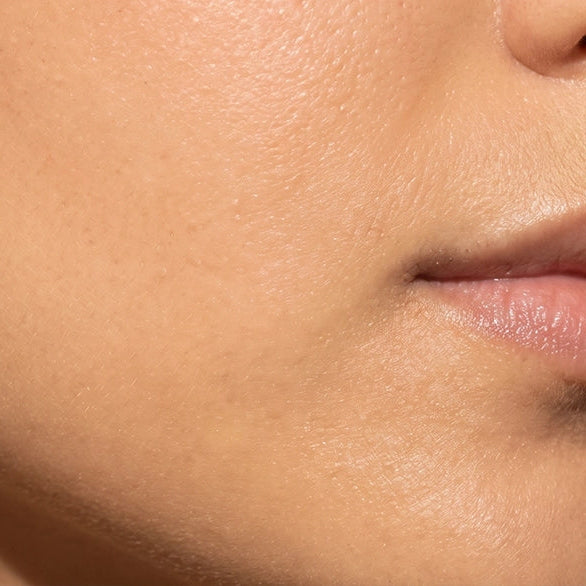 Extreme close-up of a person's lower face showing smooth skin texture, cheek, jawline, and part of the mouth.