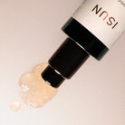 Cosmetic bottle with cream being pumped out on a light background