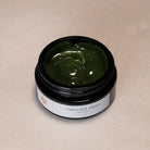 Jar of emerald algae face mask on a beige background