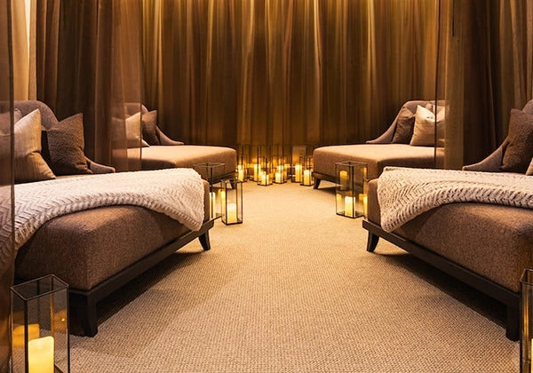 Luxury spa room with massage beds, candles, and warm lighting.