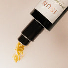 ISUN skincare product with yellow serum being dispensed onto a beige background
